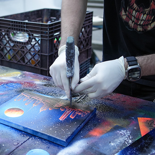 Hands at work adding detail to a spray-paint artwork